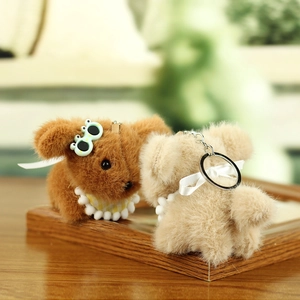 Close-up of plush puppy keychains with lace bibs and frog clips on wooden surface