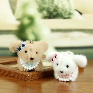 Close-up of cute plush puppy keychains with tiny glasses and plaid bibs on wood surface