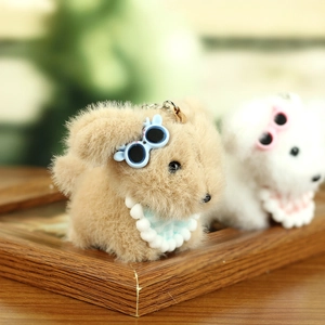 Close-up of cute plush puppy keychain with round sunglasses and pearl necklace