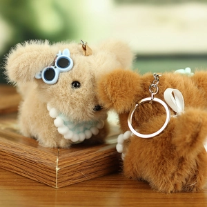Close-up of cute plush puppy keychains with sunglasses and bows on a wooden surface