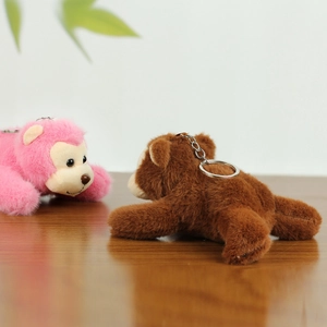 Detail of plush monkey keychains in pink and brown with silver metal rings on wood