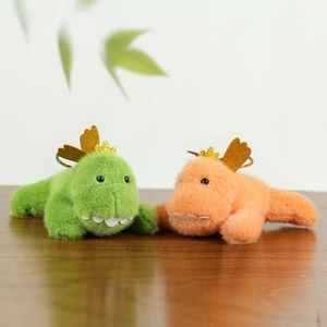 Detail of plush dinosaur charms in green and pink with golden wings on wood texture