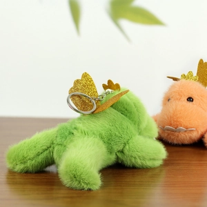 Close-up of plush dinosaur keychains in green and pink with sparkling golden wings