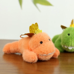Macro shot of orange dinosaur plush keychain featuring a golden crown and soft fur texture