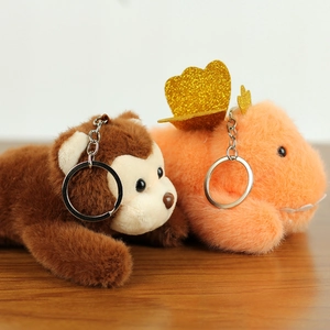 Detail of plush monkey and orange dinosaur keychains with golden glitter wings