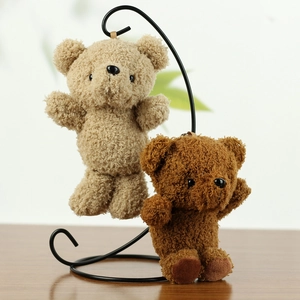 Detail of dark brown and beige plush teddy bear keychains hanging on a metal stand