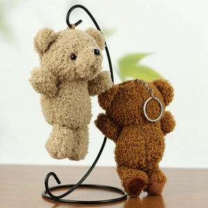 Detailed close-up of beige and brown plush teddy bear keychains hanging on a metal rack