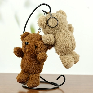 Detail of plush teddy bear charms in dark brown and beige with metallic keychains