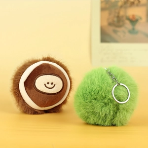 Close-up of cute plush chestnut keychain with embroidery and fluffy green ball pendant