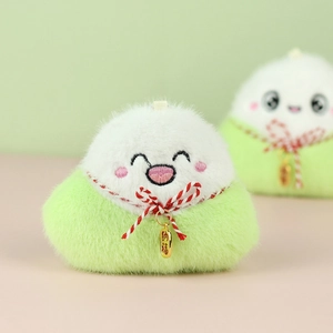 Détail d'un porte-clés zongzi en peluche avec visage brodé et étiquette dorée