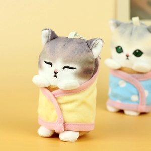 Close-up of cute plush cat keychain with gray tabby stripes and yellow wrap blanket