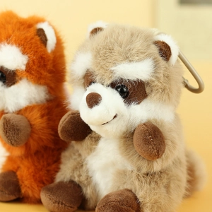 Close-up of fluffy raccoon plush keychains in orange and grey with metal clasps