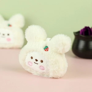 Dettaglio di un portachiavi a coniglio in peluche bianco con ricamo di fragola e texture
