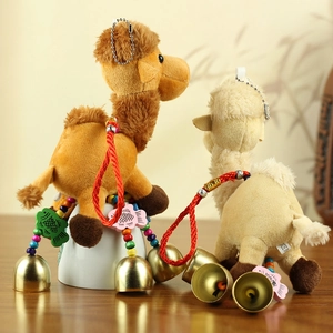 Detail of plush camel keychain with colorful beads, wooden fish decor and large metal bell