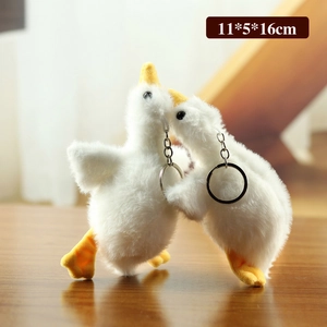 Cute white goose plush keychain set with soft fur and metal ring on wooden surface