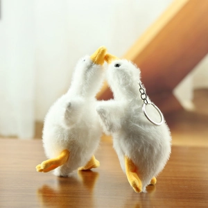 Close-up of two soft white plush goose pendants with yellow beaks and keyrings