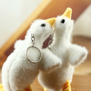 Close-up of a pair of cute white plush goose keychains with soft faux fur and metal rings