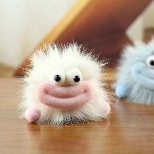 Gros plan sur le porte-clés monstre en peluche blanc avec de grands yeux et des lèvres