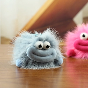 Gros plan d'un porte-clés monstre en peluche bleue avec de gros yeux et une bouche