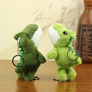 Nahaufnahme süßer grüner Plüsch-Dinosaurier-Anhänger auf Holzoberfläche mit Ringen
