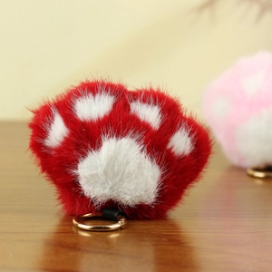 Gros plan d'un pendentif patte de chat en peluche rouge avec boucle métallique dorée