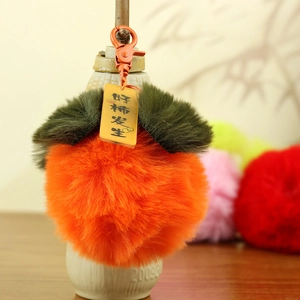 Dettaglio portachiavi a forma di caco in peluche con chiusura arancione e targhetta