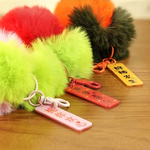 Dettaglio di portachiavi colorati in peluche con ciondoli decorativi su legno