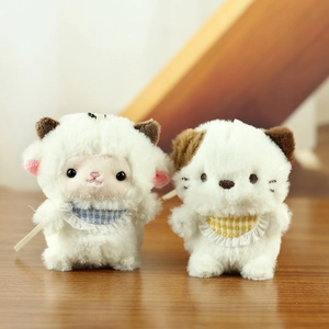 Cute plush keychain dolls of a white lamb and spotted animal with plaid bibs on wood