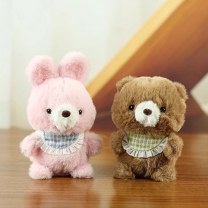 Cute plush bunny and bear keychain set with decorative bibs on a wooden surface