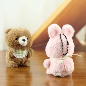 Close-up of cute plush bear with green collar and pink rabbit toy keychain set