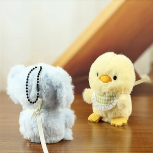 Close-up of fluffy yellow chick and blue bear plush pendants with lace bibs and bead chains
