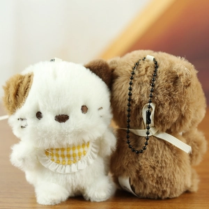 Close-up of plush dog and brown bear keychains with yellow bib on a wooden surface