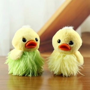 Cute plush duck keychains in green and yellow colors on a rustic wooden background
