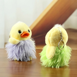 Detail of plush duck keychains with purple and green long faux fur on wooden surface