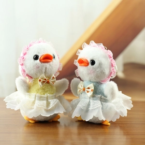 Detail of plush duck keychains with lace dresses and checkered hats in soft lighting