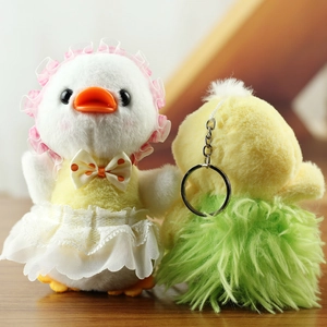 Detail of plush duck keychain with lace dress and metal hook on warm wood background