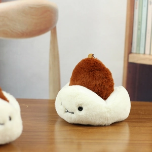 Close-up of white plush bun keychain with brown pom-pom on a warm wooden surface