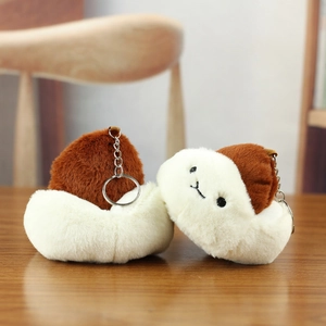 Detail of plush bun charms with metal keychains on a warm wooden background