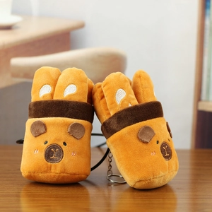 Close-up of cute plush capybara charms with soft fabric and metal hooks on wooden table