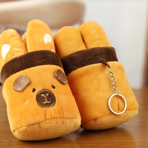 Close-up of soft plush Capybara baguette charm with metal keychain on wooden surface