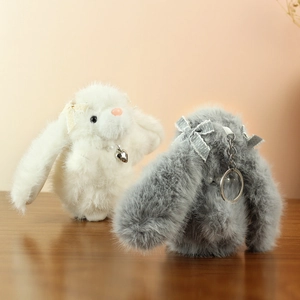 Detail of plush bunny keychains in white and grey with lace bows and heart charms