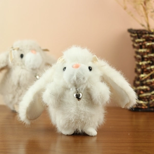 Detailed macro of white plush bunny toy featuring a pearl heart pendant and soft fur texture