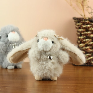 Close-up of soft faux fur bunny keychain with heart pendant on a wooden table