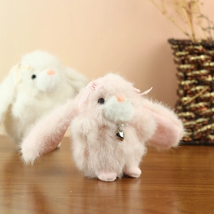 Close-up of pink plush rabbit charm with pearl necklace and heart pendant detail