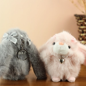 Detail of plush bunny keychains with bow ties and pearl necklace in grey and pink