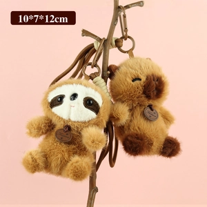 Dettaglio di ciondoli in peluche bradipo e capibara con etichette su sfondo rosa
