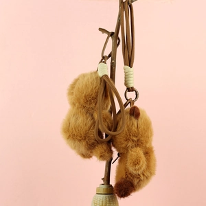 Dettaglio di ciondoli panda di peluche marrone con cordini su un ramo di legno