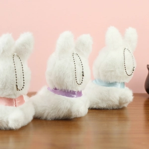 Dettaglio di tre portachiavi a forma di coniglio in peluche con fiocchi rosa e viola