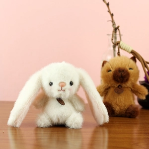 Dettaglio di portachiavi a forma di panda e coniglio in peluche su sfondo legno