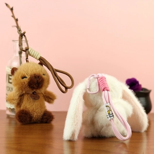 Dettaglio di ciondoli in peluche a forma di capibara e coniglio con cordini intrecciati